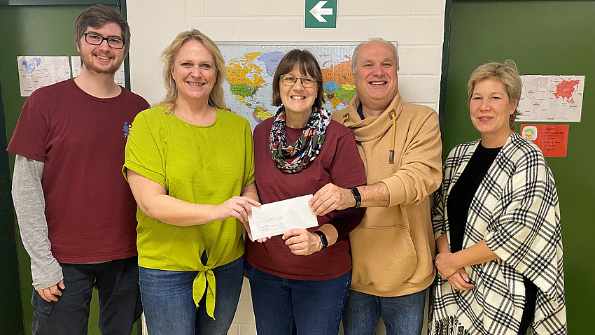 Drei Frauen und zwei Männer halten einen Brief in den Händen. Sie lächeln in die Kamera.
