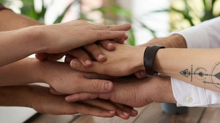 Sieben Hände von verschiedenen Personen, die übereinander gelegt sind