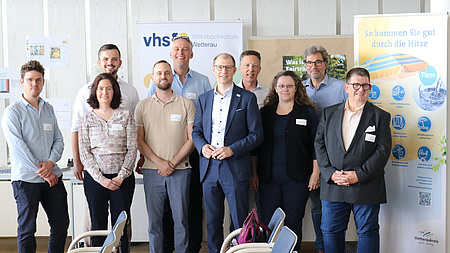 Mehrere Erwachsene stehen vor einem Infostand.