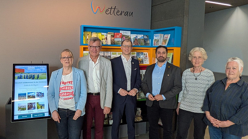 Eine Gruppe von Leuten vor einem digitalen Infodisplay.