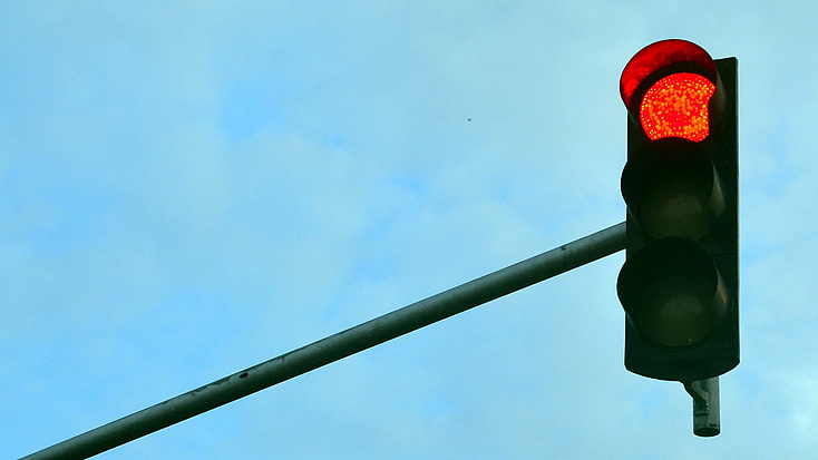 Eine rote Ampel vor blauem Himmel