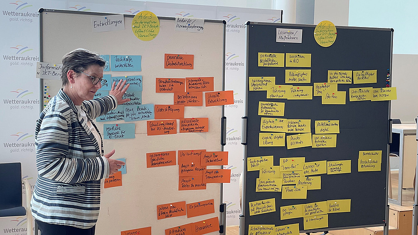 Eine Frau steht in einem Saal vor zwei Stellwänden mit zahlreichen Notizzetteln.