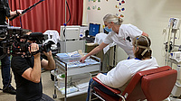 Die Patientin im Gespräch mit dem Arzt. Daneben ein Kameramann und ein Techniker, der ein Mikrofon hält.