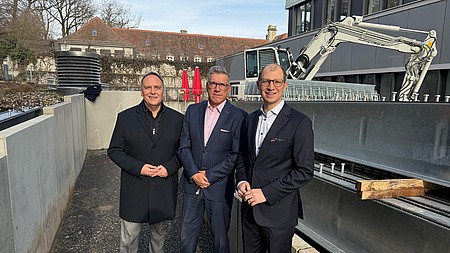 Bürgermeister Klaus Kreß, GZW-Geschäftsführer Dr. Dirk M. Fellermann und Landrat Jan Weckler. Sie stehen vor einer Baustelle.