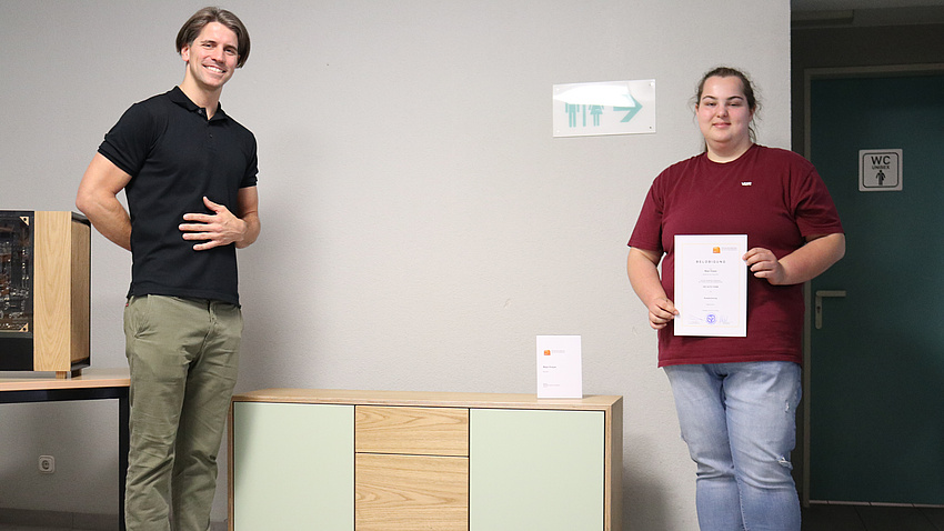 Zwei Menschen stehen vor einem Sideboard.