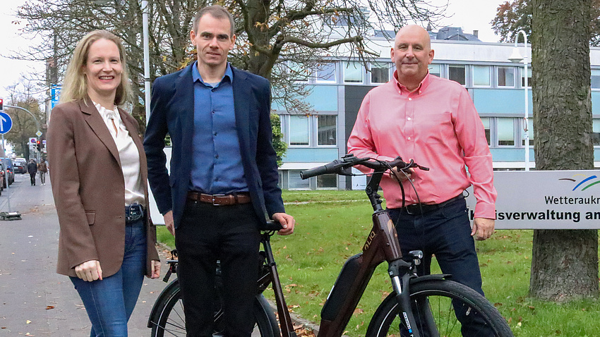 Birgit Weckler, Julian Herzel und Volker Matthesius stehend am Europaplatz, davor ein Fahrrad.