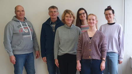 Die Personen lächeln in die Kamera.