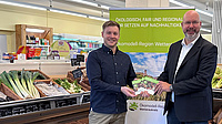 Matthias Walther und Yannik Rudolf halten den Einkaufsführer in der Hand. Im Hintergrund ist ein Roll-Up zu sehen.