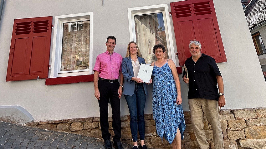 Vier Menschen stehen vor einem alten Fachwerkhaus.