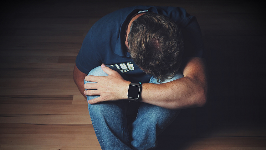 Mann kauert sich zusammen.