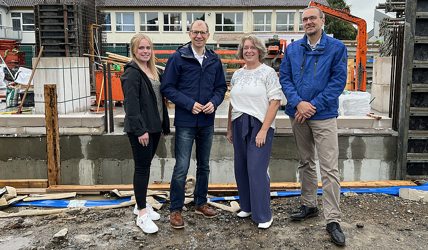Die vier Personen stehen vor einer Baustelle.