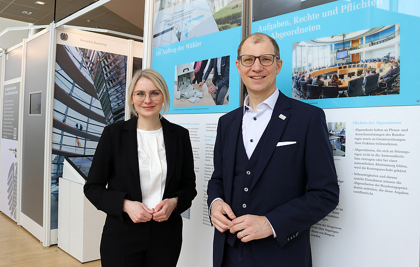 Ein Mann und eine Frau stehen vor einer Ausstellungswand.
