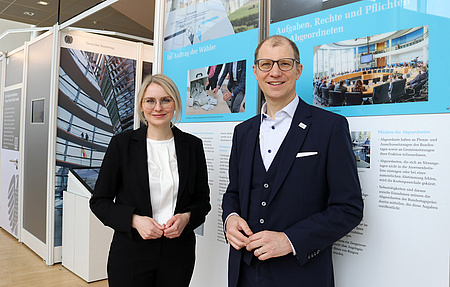 Ein Mann und eine Frau stehen vor einer Ausstellungswand.