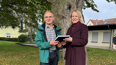 Adam Strecker übergibt den Untersuchungsbericht an Birgit Weckler.