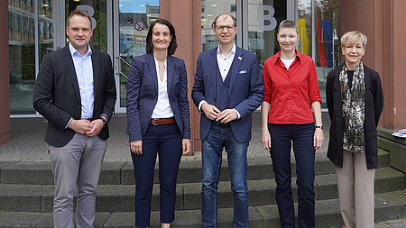 Fünf Personen vor einem Gebäude.