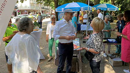 Mehrere Menschen stehen auf einer Einkaufsstraße und unterhalten sich.