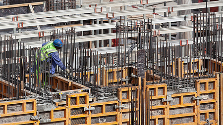 Ein Bauarbeiter bereitet auf einer Baustelle das Gießen von Betonwänden vor.