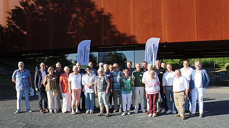 Eine größere Personengruppe steht auf dem geschotterten Paltz vor dem Keltenmuseum am Glauberg. Alle blicken in die Kamera