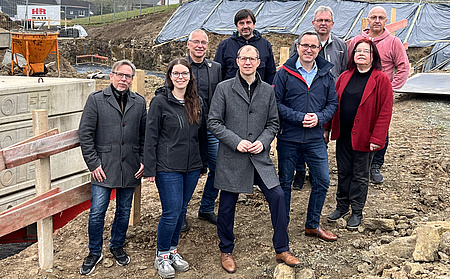 Eine kleine Personengruppe steht auf einer Baustelle.