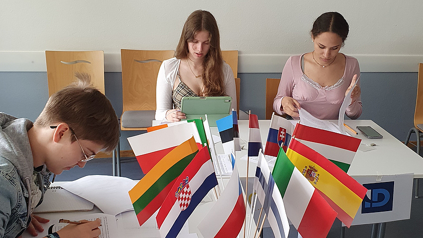 Zwei Schülerinnen und ein Schüler arbeiten konzentriert an Aufgaben.