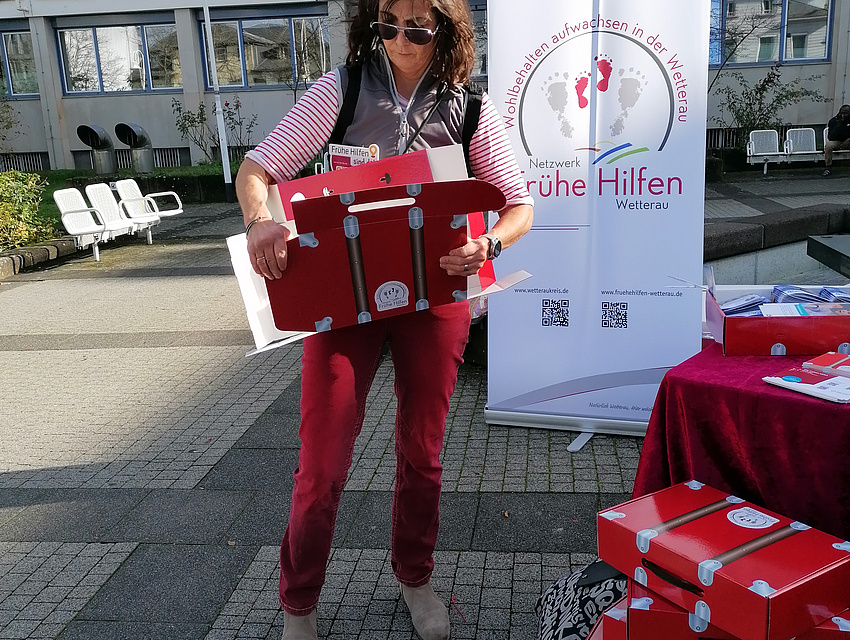 Eine Familienhebamme packt Infomaterialien in das rote Köfferchen.