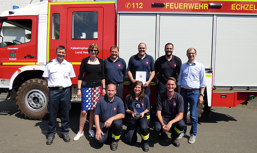 Eine Gruppe Männer und Frauen steht vor einem Löschfahrzeug der Freiwilligen Feuerwehr Echzell.