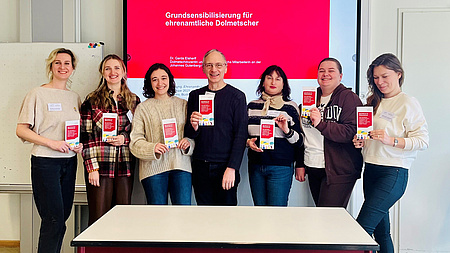 Eine Gruppe von Leuten. Sie halten ein Dokument in der Hand und lächeln.