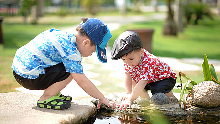 Zwei kleine Jungen spielen am Wasser