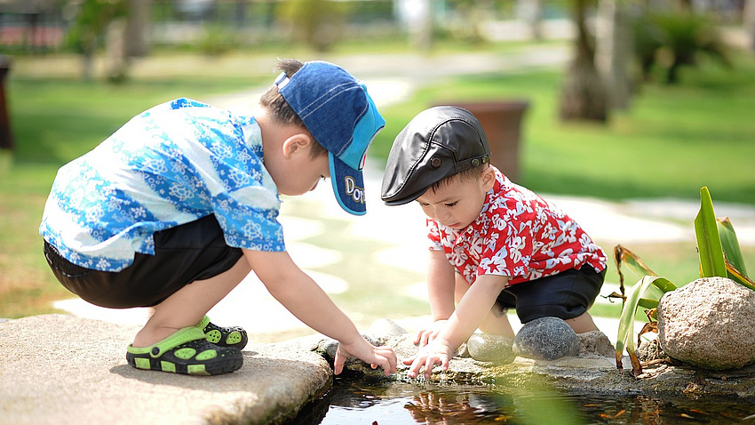 Zwei kleine Jungen spielen am Wasser