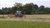 Ein Traktor bei der Wiesenmahd auf dem Grünland.