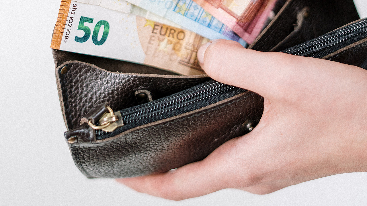 Hand hält Portemonnaie mit Geldscheinen.