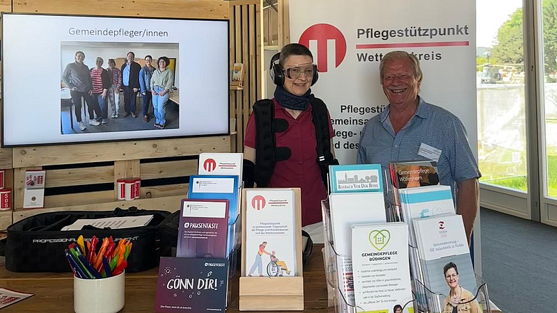 Zwei Personen, eine davon im Alterssimulationsanzug mit Brille