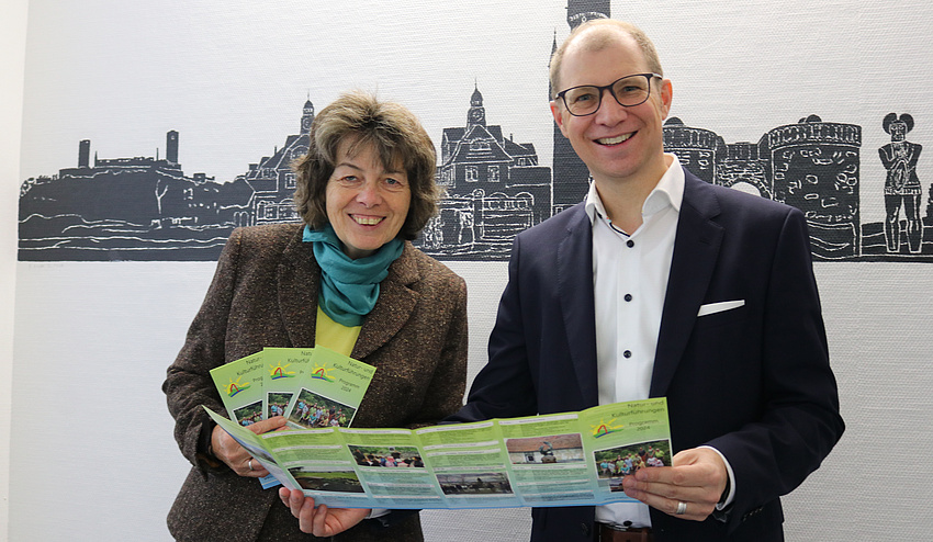 Ein Mann und eine Frau halten gemeinsam ein Prospekt in der Hand.