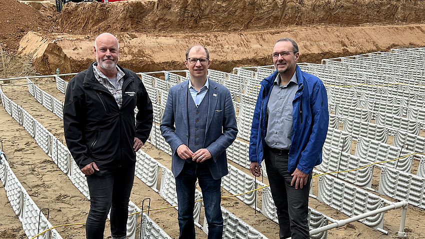 Drei Männer stehen auf einer Baustelle.