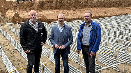 Drei Männer stehen auf einer Baustelle.