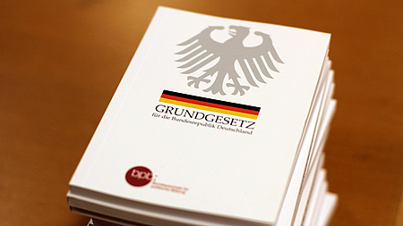 Auf einem Stapel liegen mehrere gebundene Ausgaben des Grundgesetzes für die Bundesrepublik Deutschland.
