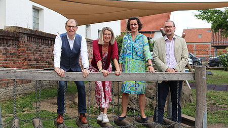 Zwei Männer und zwei Frauen stehen unter einem Sonnensegel.