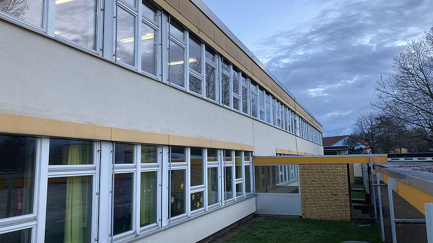 Ein längliches Schulgebäude mit vielen Fenstern.