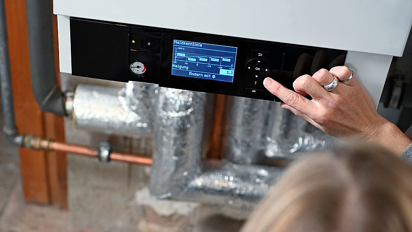 Das Bild zeigt eine Hand, die Einstellungen an der Heizung vornimmt.