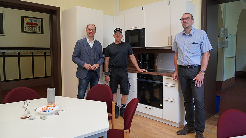 Landrat Jan Weckler, Jörg Till und Alexander Hiemer stehen vor einer neuen Küchenzeile.