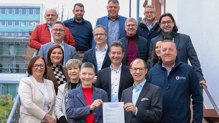 Eine Gruppe von Leuten hat sich auf einer Treppe aufgestellt und lächelt in die Kamera.