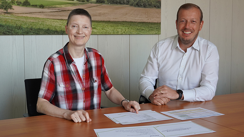 Marion Götz und Martin Langlitz an einem Tisch mit Unterlagen.