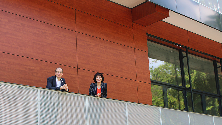 Ein Mann und eine Frau stehen auf dem Balkon eines Schulgebäudes