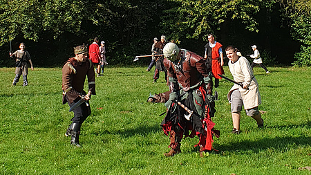 Eine Gruppe von Jungen in mittelalterlicher Gewandung auf einer Wiese.