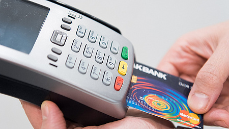 Ein Mann steckt eine Girocard in ein elektronisches Zahlungsgerät.