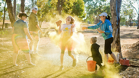 Eine Familie im Sonnenschein, die sich mit Farbbeuteln bewirft