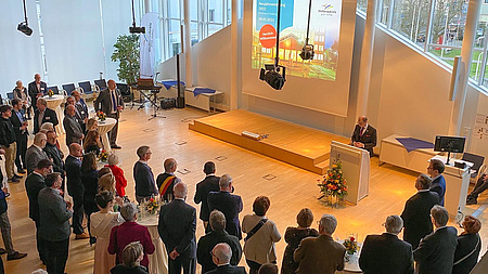 Blick von oben in den Plenarsaal des Kreishauses. Landrat Jan Weckler steht am Rednerpult. Davor, in einem Halbkreis, die zuhörenden Gäste.