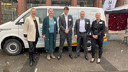 Drei Frauen und zwei Männer stehen vor einem großen weißen Auto, dem Beratungsbus der Jugendberufsagentur.