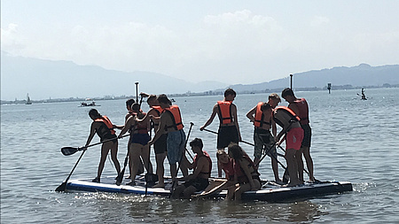 Junge Menschen auf einem Surfboard und Paddeln auf dem See