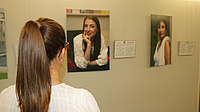 Eine Frau sieht sich in einem Raum an der Wand hängende Foto-Porträts an.